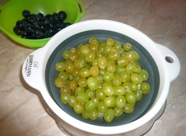 Мытый зеленый виноград столового сорта в чашке и плошка с синим виноградом