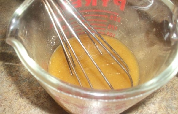 Приготовление заправки для моркови в металлической миске с венчиком
